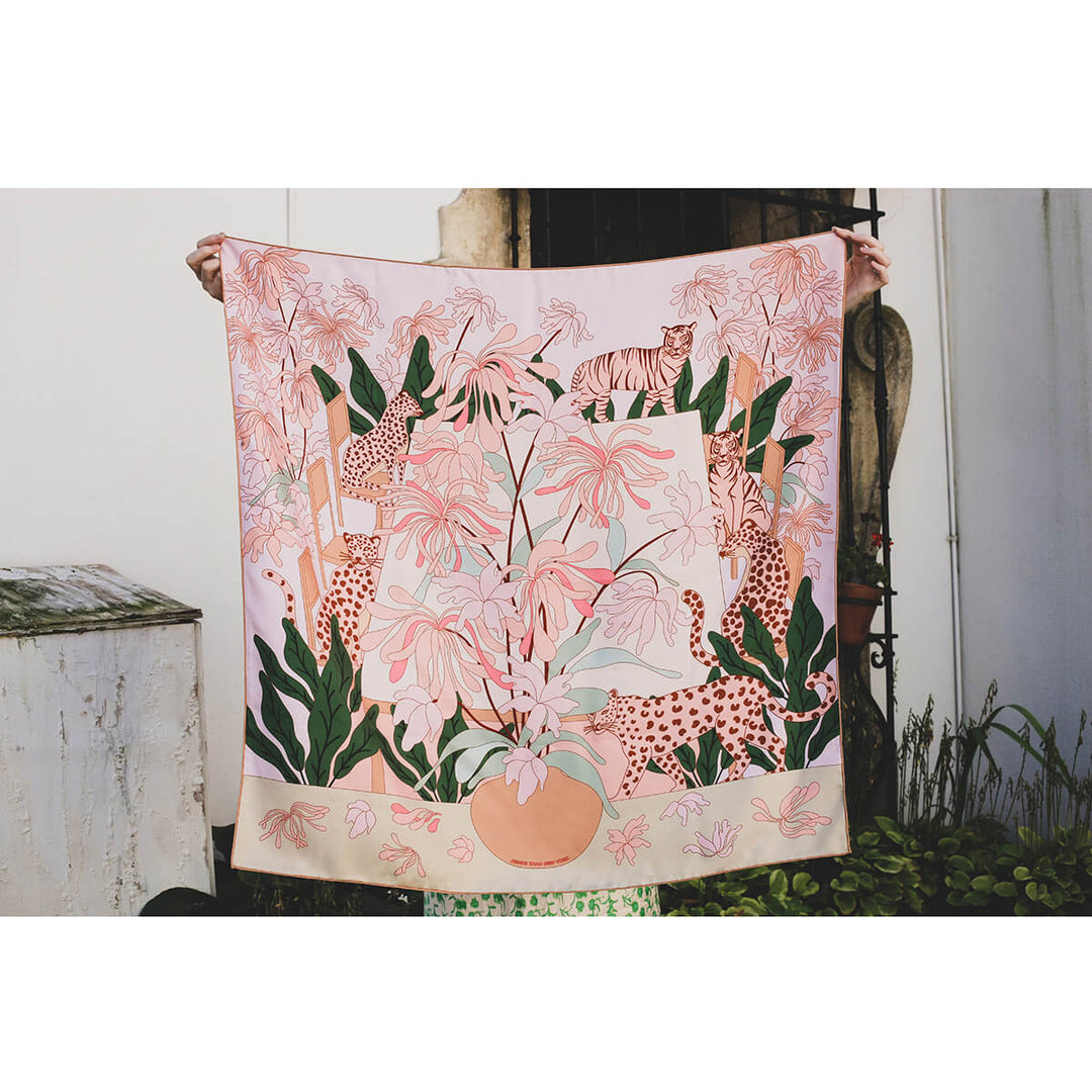 Model presents Jessie Zhao's jungle-inspired silk scarf in pink with big cats and foliage.